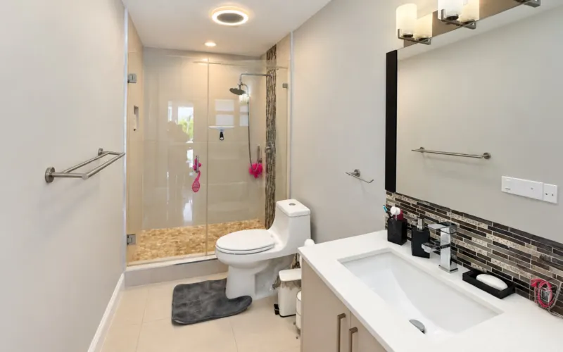 Bathroom with a glass shower, mosaic strip and a white-top vanity