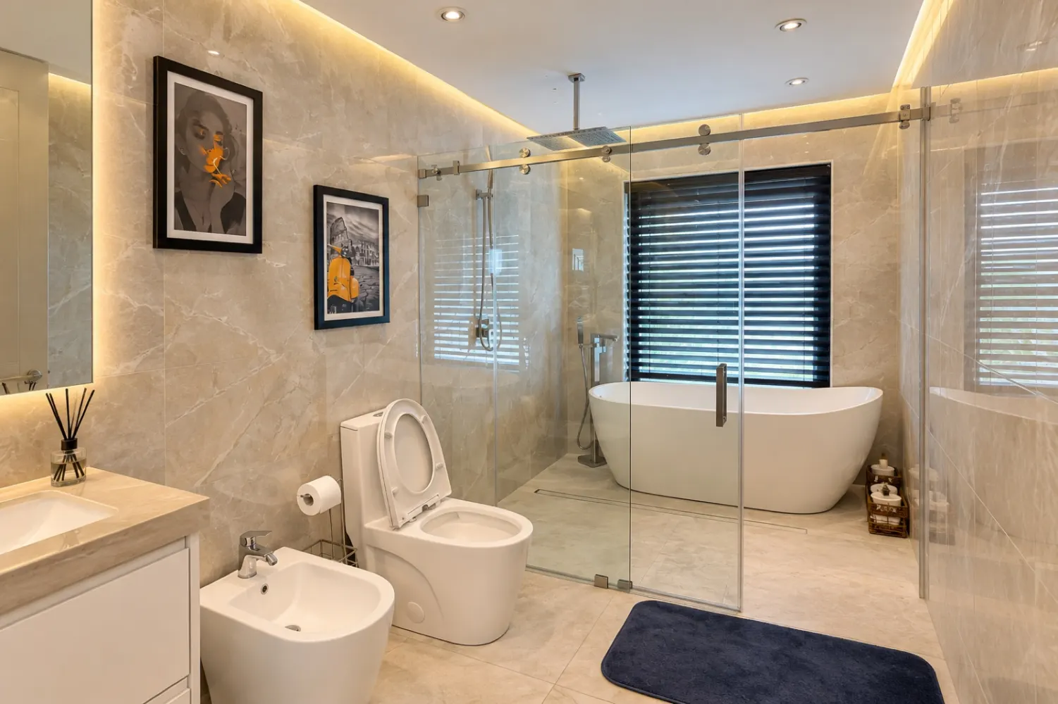 Bathroom with tub and shower behind glass, toilet and bidet