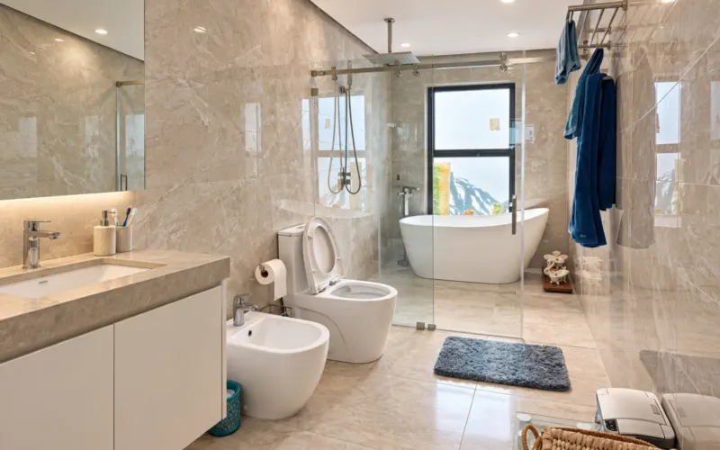Vanity with a backlit mirror and the tub in the background
