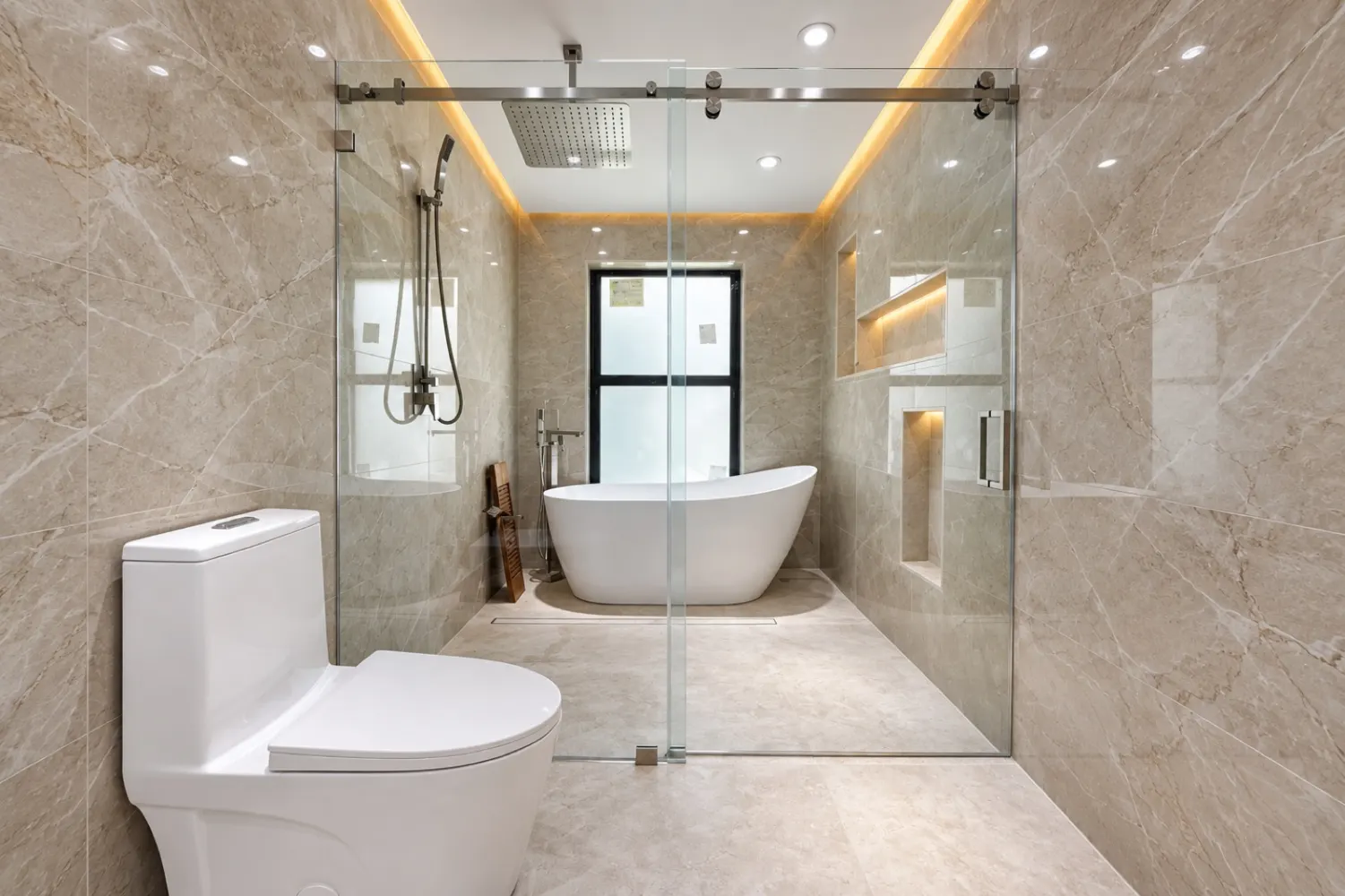 Bathroom with a freestanding tub and shower behind a glass enclosure, with lighting built into the ceiling and niches