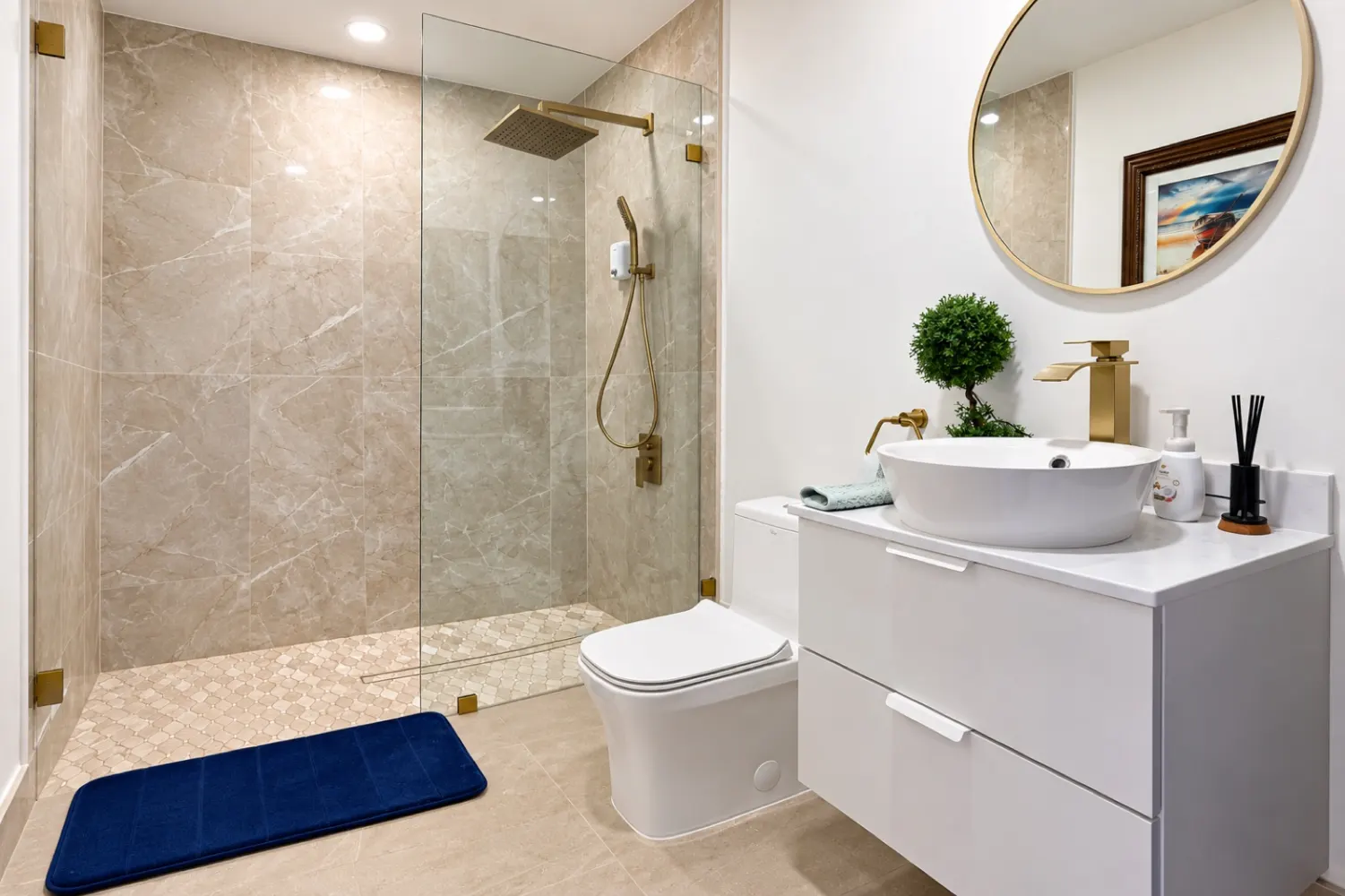 Bathroom with a walk-in shower, gold fixtures, vessel sink and round mirror