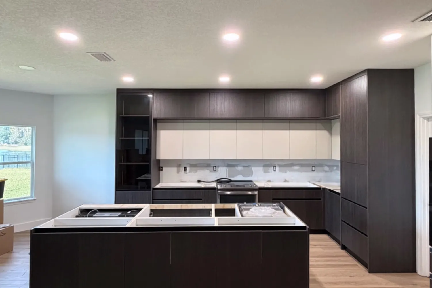 Kitchen 3: island and tall towers in dark wood, being assembled