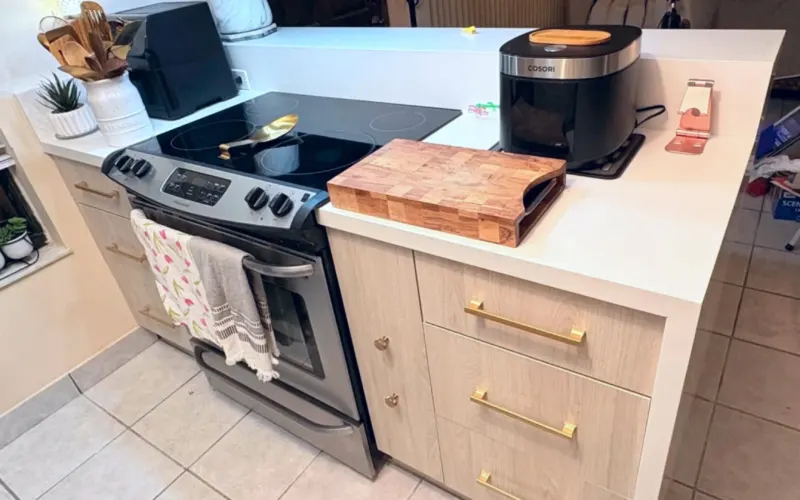 Después: gavetas en madera clara con tiradores dorados y countertop blanco