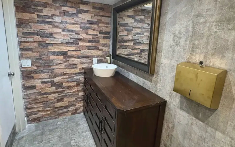 After: stone wall, wood vanity and vessel sink