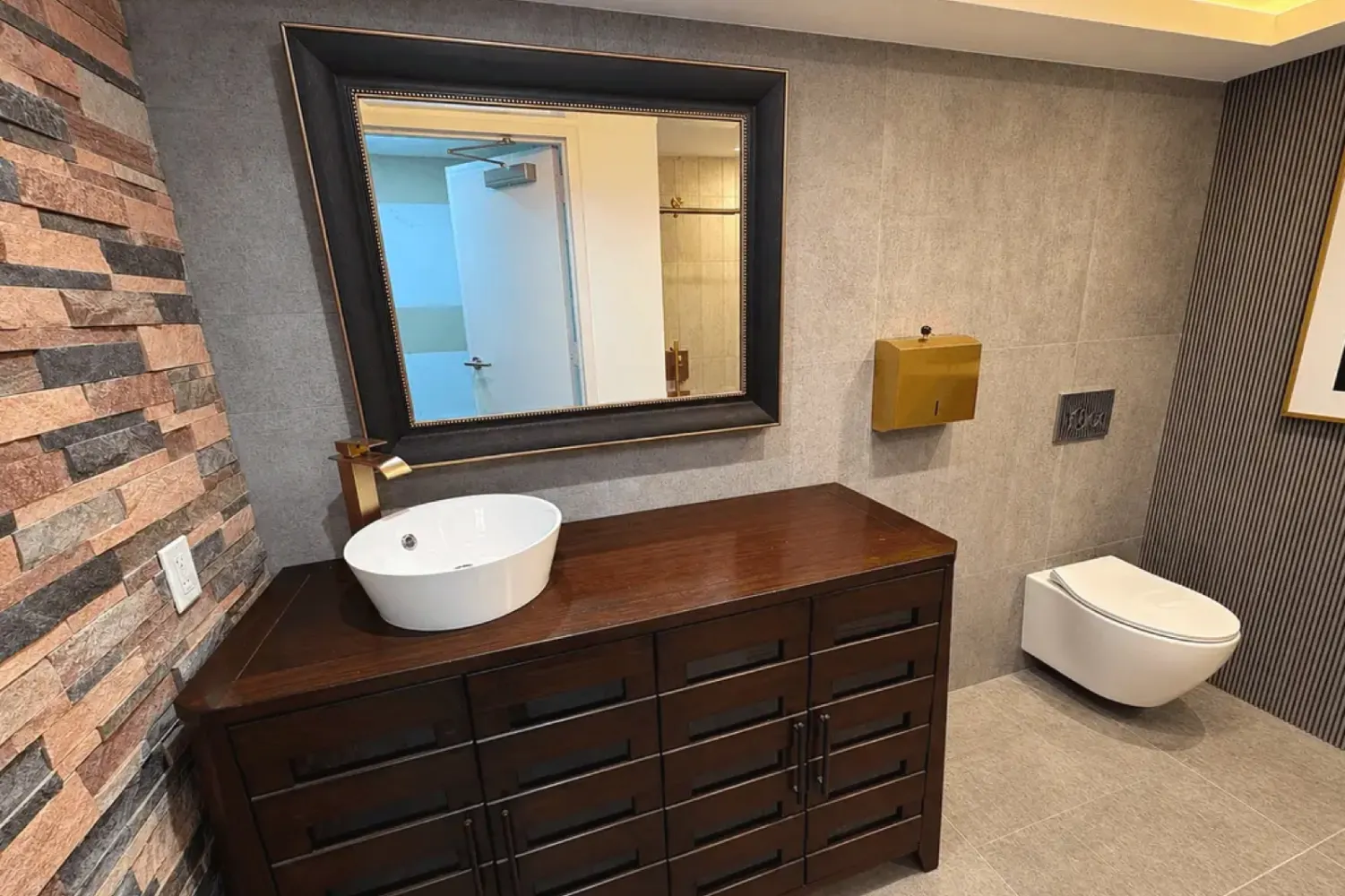 After: wood vanity with mirror, gold faucet and floating toilet