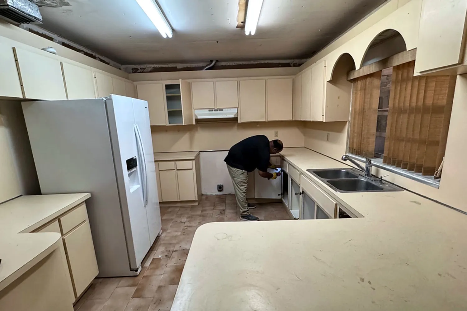 Before: U-shaped kitchen with cream cabinets, laminate countertop and fluorescent lighting