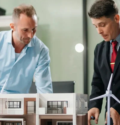 Modern office meeting of architects, designers, and developers creating innovative, sustainable housing projects using building models and digital tools.